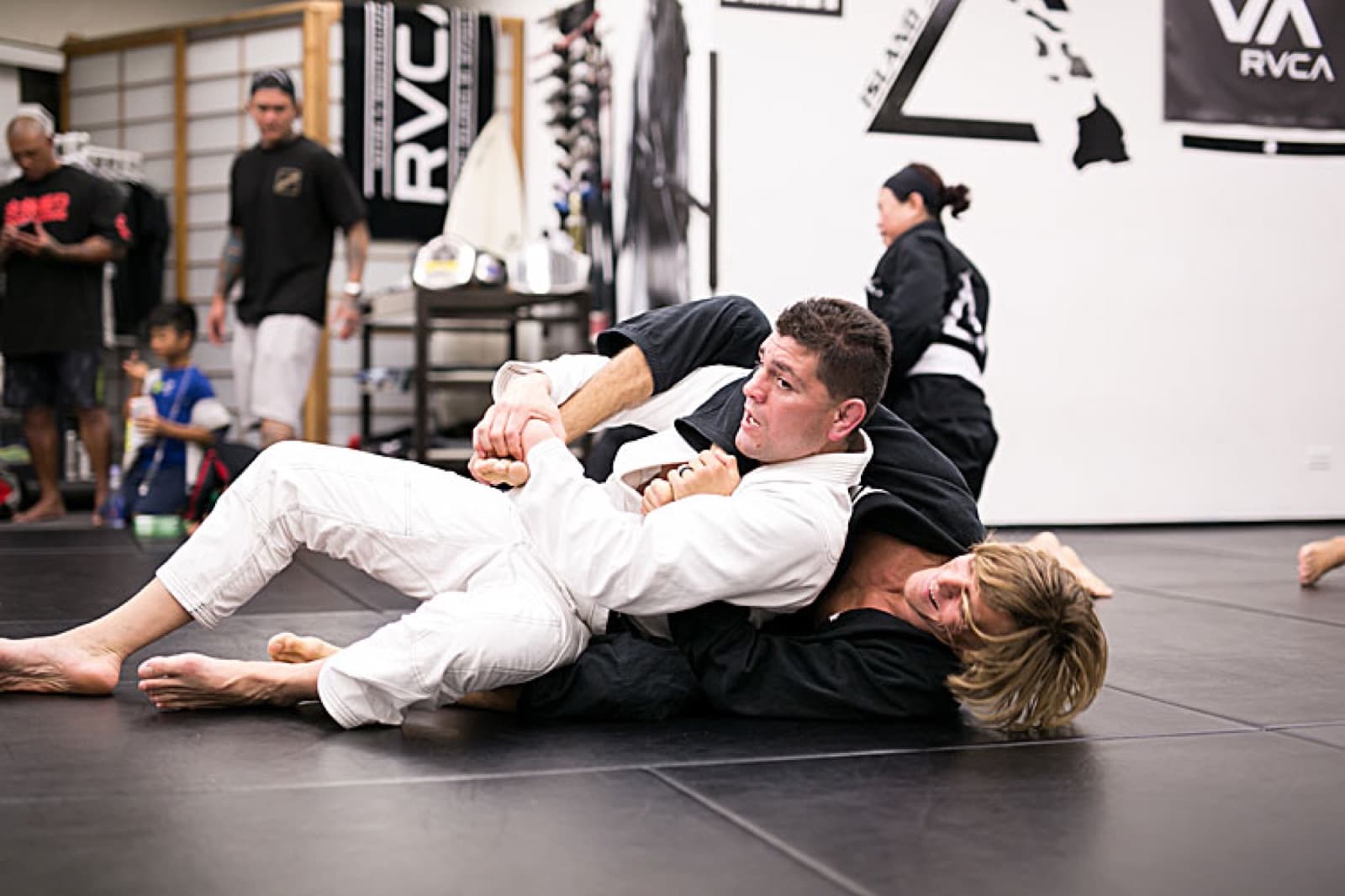 Two adult students working a sweep on the black mats at Island Jiu-Jitsu