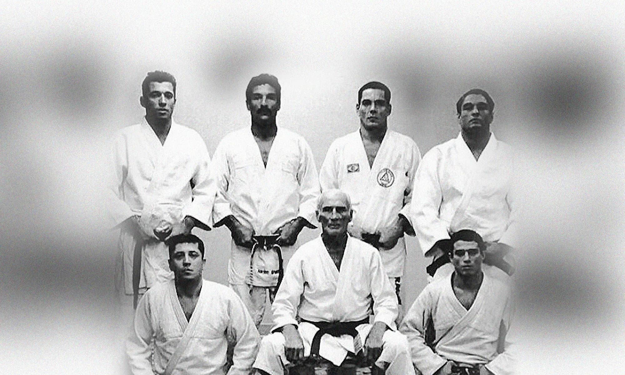 Black-and-white portrait of Helio Gracie seated with members of the Gracie family in their gis